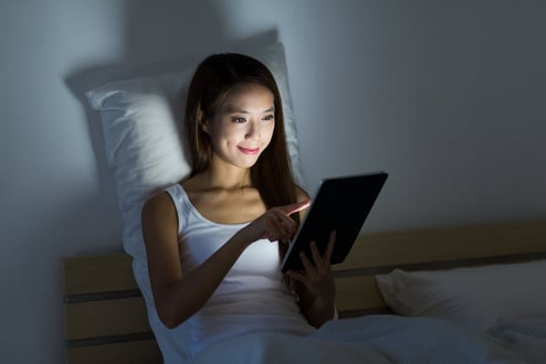 woman reading at night on her tablet